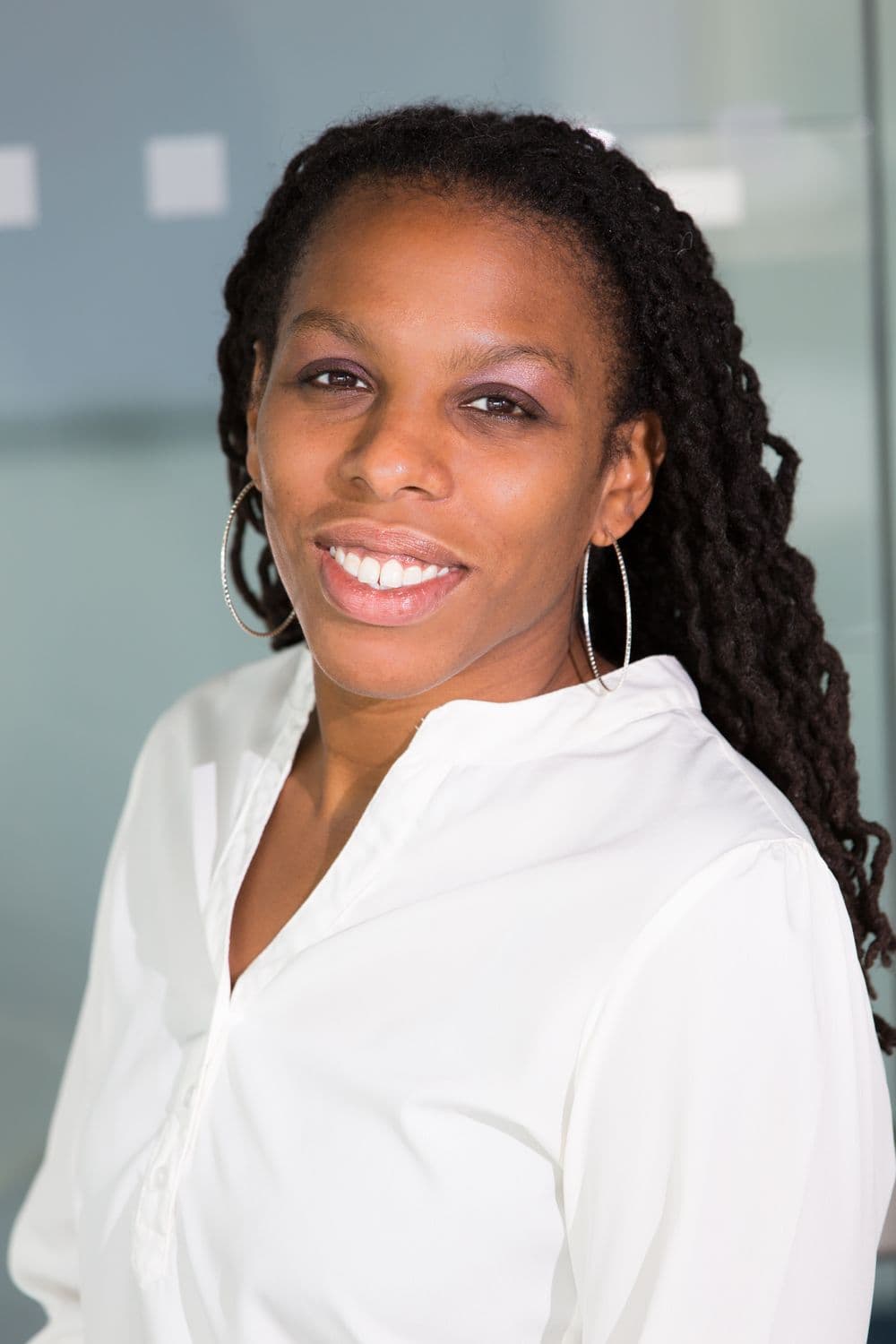 Portrait of Amara Okoye, smiling, in a white blouse in soft natural light