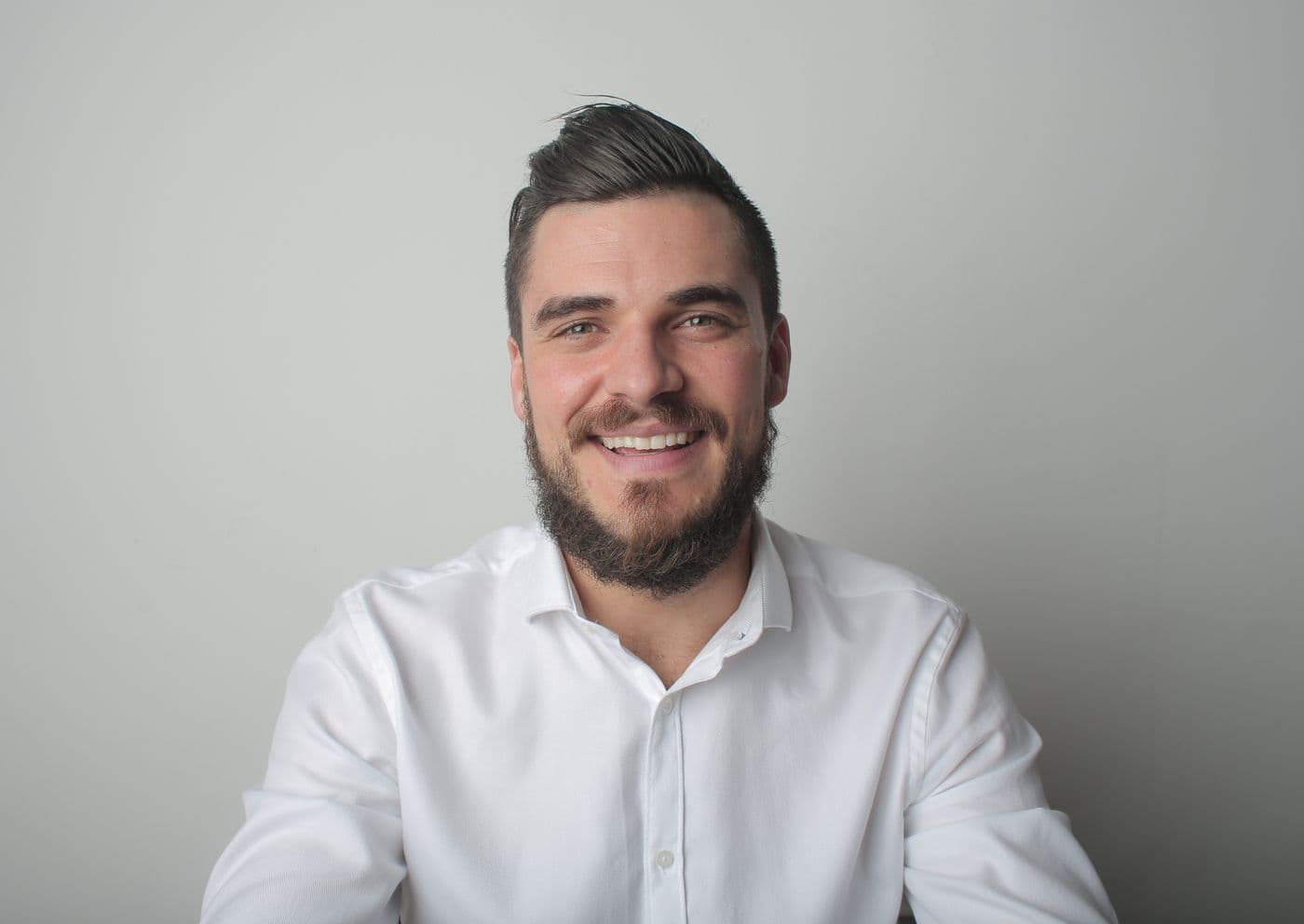 Portrait of Daniel Brandt, smiling, with a beard and a white shirt
